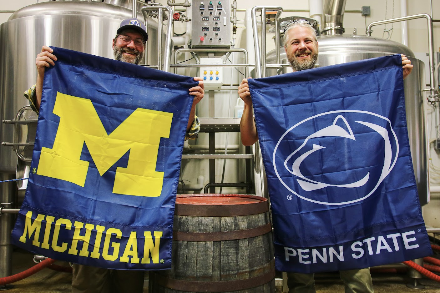 Two people holding a University of Michigan banner and Penn State banner